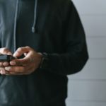 Mãos operando um smartphone em ambiente interno, em uma situação de uso de pagamento digital.