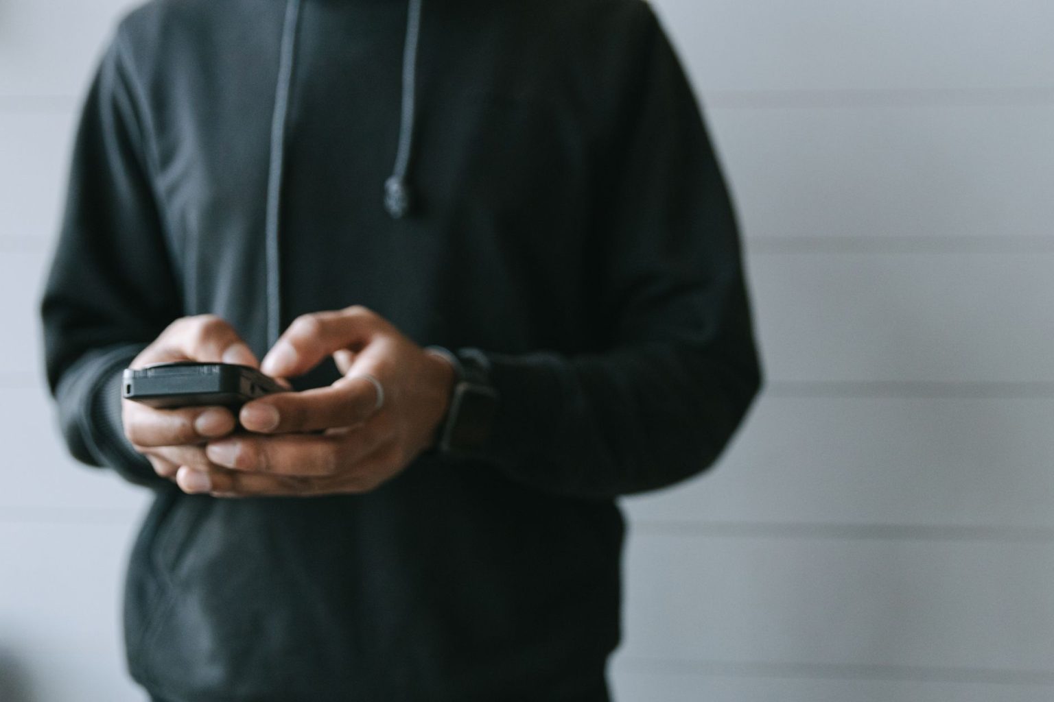 Mãos operando um smartphone em ambiente interno, em uma situação de uso de pagamento digital.
