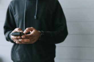 Mãos operando um smartphone em ambiente interno, em uma situação de uso de pagamento digital.